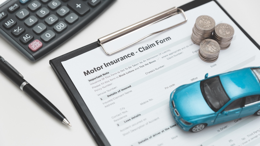 car insurance claim form with coin stack, calculator and car model