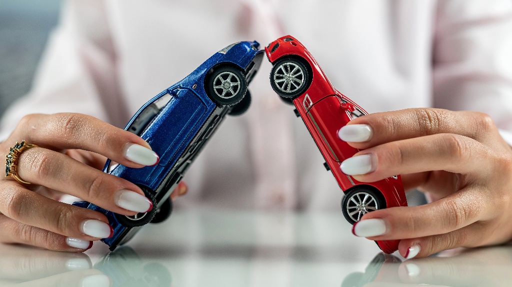 woman simulating an accident with two mini cars on the table