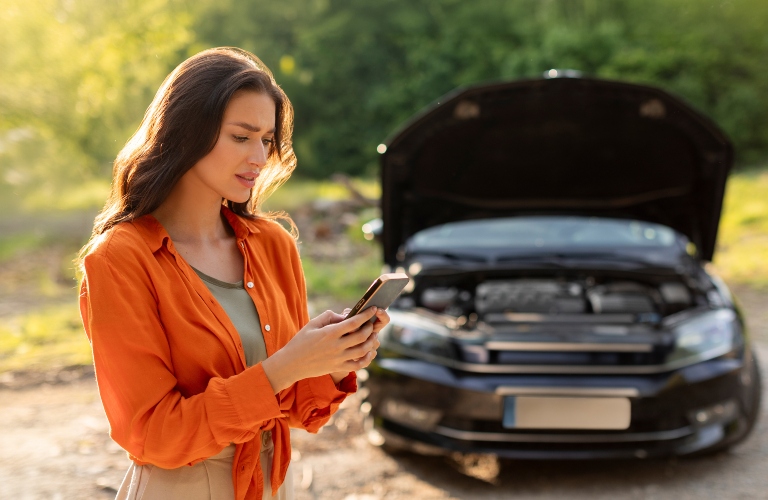 Sad woman has broken down car on roadside, feeling stressed