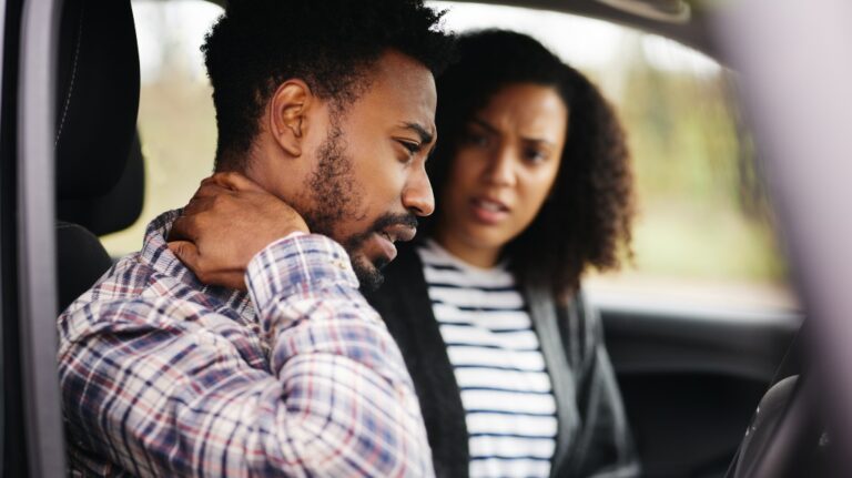 Couple inside car after road traffic accident with male driver suffering whiplash injury